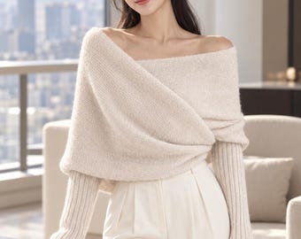 Könnte beinhalten: Ein beigefarbener schulterfreier Pullover mit weicher, flauschiger Textur, drapiertem Wickeloberteil und langen, gerippten Ärmeln, kombiniert mit einer cremefarbenen Hose mit hoher Taille und sauberer, maßgeschneiderter Vorderfalte.