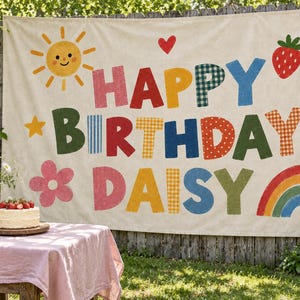 以下が含まれることがあります： クリーム色の布製バナーで、カラフルな柄入りのブロック体で「HAPPY BIRTHDAY DAISY」と書かれています。デザインには、黄色い太陽、赤いハート、2つのイチゴ、2つの黄色い星、ピンクの花、虹が描かれています。