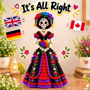 May include: A crocheted skeleton doll wearing a black dress with red and purple ruffled layers, adorned with colorful floral embroidery. The doll features a skull face with floral details, a flower crown, and holds a bouquet of vibrant flowers.