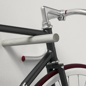 These minimal wooden bike hooks present an elegant and clever way to store your bespoke bicycle at home. A simple but sophisticated storage solution for light sports bikes. Hand-turned from sustainable hardwood. This pair comes in plain oak.