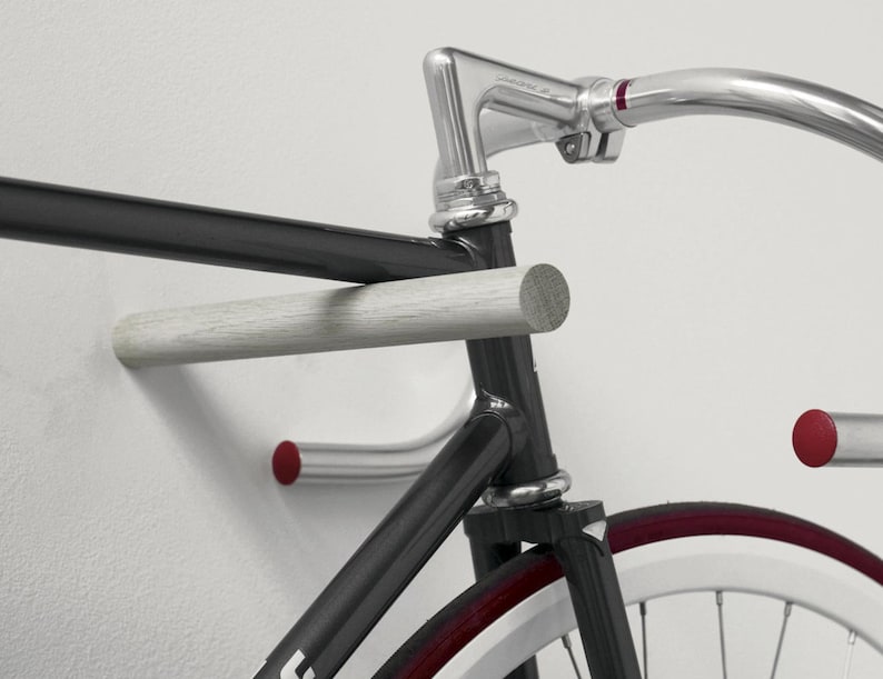 These minimal wooden bike hooks present an elegant and clever way to store your bespoke bicycle at home. A simple but sophisticated storage solution for light sports bikes. Hand-turned from sustainable hardwood. This pair comes in plain oak.