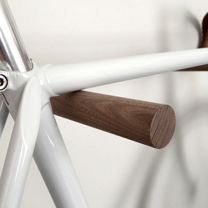 This pair of wooden bike hooks comes in black walnut wood. The wall mounted hooks hold a minimalistic sports bike in light grey. Only recommended for bicycles up to 13 kg.