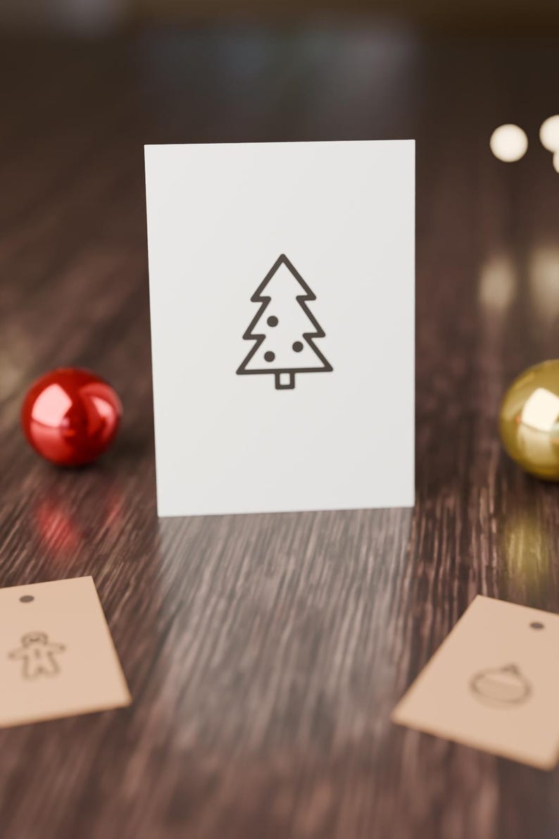May include: A white rectangular card featuring a centered black line drawing of a Christmas tree with circular ornaments. Two tan rectangular gift tags with simple black line icons of a gingerbread man and a bauble are positioned below.