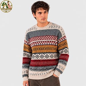 May include: A long-sleeve crew neck sweater featuring a multi-colored horizontal pattern with bands of red, mustard yellow, gray, and white. The knit design includes geometric shapes, diamonds, and chevron motifs across the chest and sleeves.