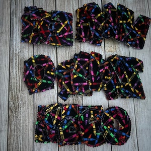 Pode incluir: Um conjunto de letras de feltro que soletram a palavra "READ" com um padr&atilde;o de giz de cera. As letras s&atilde;o pretas com desenhos de giz de cera coloridos.