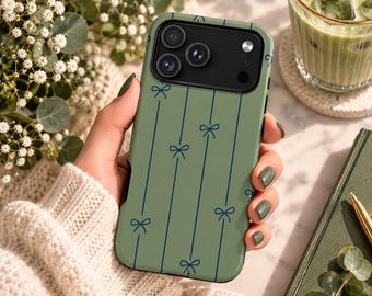 Puede incluir: Una funda para smartphone de color verde salvia con un patrón de finas líneas verticales azul oscuro acentuadas con pequeñas y delicadas ilustraciones de lazos. La funda tiene un recorte negro para el módulo de cámara de varias lentes.