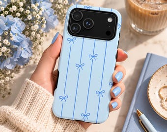 Puede incluir: Una funda para smartphone de color azul claro con un patrón de líneas verticales y pequeños lazos azul oscuro. La funda tiene un área de recorte negra para la cámara con tres lentes circulares y un flash para un smartphone.