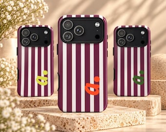 Puede incluir: Tres fundas para smartphone con un patrón de rayas verticales en granate y blanco. Cada funda tiene un módulo de cámara negro y una letra a minúscula seguida de un punto en diferentes colores: verde lima, naranja y verde bosque.