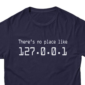Peut inclure: Un t-shirt bleu marine avec du texte blanc qui dit "There's no place like 127.0.0.1".
