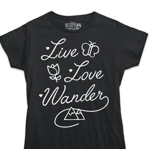 K&ouml;nnte beinhalten: Schwarzes T-Shirt mit wei&szlig;em Text "Live Love Wander" mit einem Schmetterling, einer Blume und einem Bergmotiv.
