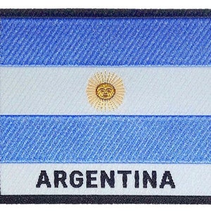 May include: A blue and white embroidered patch featuring the Argentinian flag and the word "ARGENTINA" in black lettering.