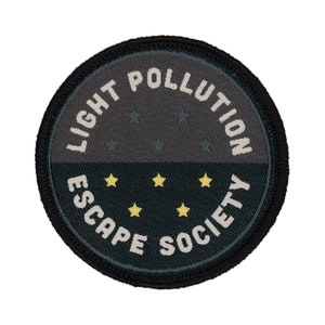 May include: A black and grey circular patch with white text that reads "Light Pollution Escape Society". The patch has a dark grey background with white stars and a dark green background with yellow stars.