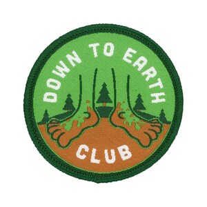 Peut inclure: Écusson brodé vert avec du texte blanc qui dit "Down to Earth Club". L'écusson présente une image de dessin animé de deux pieds avec des arbres qui poussent hors d'eux.