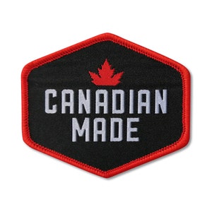 Peut inclure: Un écusson hexagonal noir avec une feuille d'érable rouge et le texte "CANADIAN MADE" en blanc.