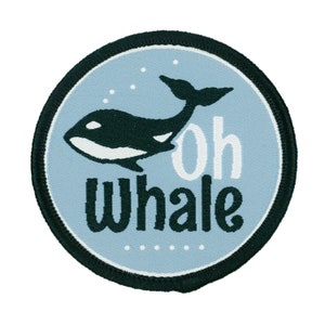 May include: A round, blue and black fabric patch with a white outline. The patch features a black and white orca whale with the text "oh whale" in white.