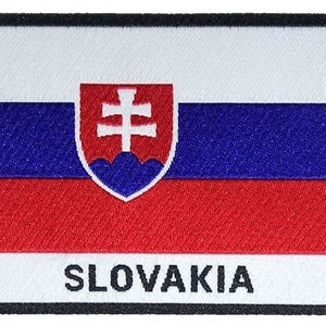 May include: Embroidered patch of the Slovakian flag. The design features horizontal stripes in white, blue, and red, with the Slovak coat of arms on the left. The word "SLOVAKIA" is displayed in black text at the bottom, set against a white background.