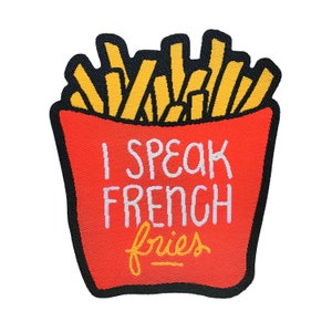 Peut inclure: Patch brodé rouge et jaune avec une image de dessin animé d'un contenant de frites et le texte "Je parle français frites".