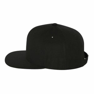 Puede incluir: Una gorra de b&eacute;isbol negra con visera plana y corona estructurada.