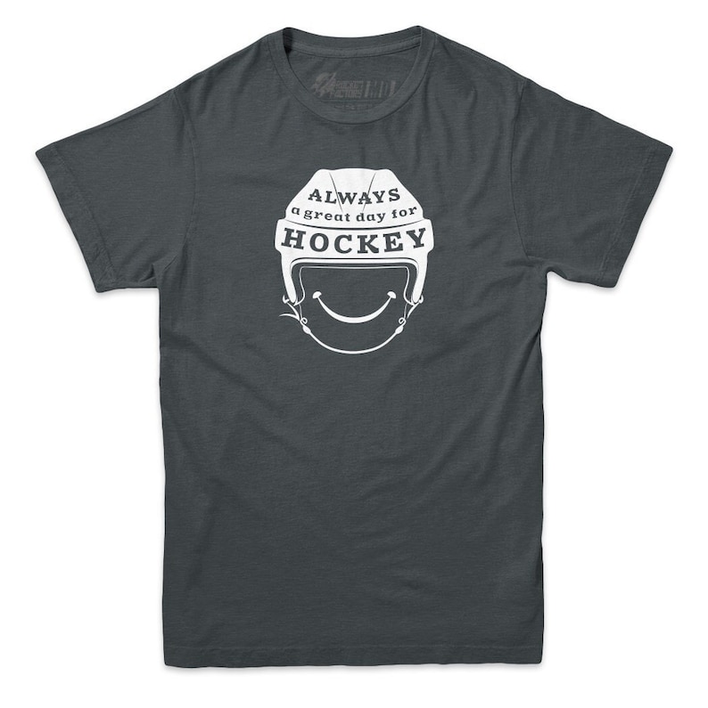 May include: A dark gray t-shirt with a white graphic of a hockey helmet with a smiling face and the text "ALWAYS a great day for HOCKEY".