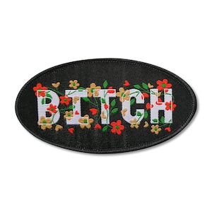 May include: Black oval patch with white embroidered text that reads "BITCH" surrounded by green vines and red and yellow flowers.