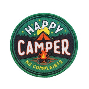 Peut inclure: Patch brodé vert, noir et orange avec le texte "Happy Camper No Complaints" et une silhouette de tente et de feu de camp.