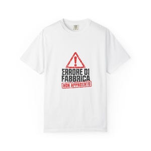 Può includere: Una t-shirt bianca a maniche corte con un triangolo di avvertimento rosso con un punto esclamativo sopra il testo nero invecchiato ERRORE DI FABBRICA e un timbro rettangolare rosso con il testo NON APPROVATO.