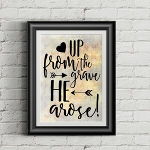 May include: Framed art print with the words "Up from the grave He arose!" in black script. The text is set against a background of vintage sheet music. A black heart and arrows accent the text. The frame is black.