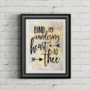 Pode incluir: Uma impressão emoldurada em preto com fundo branco e texto preto que diz "Bind my wandering heart to thee". O texto está em uma fonte de escrita à mão e é acompanhado por duas flechas pretas apontando para a direita.
