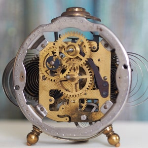 May include: A vintage silver alarm clock with a clear face revealing the intricate gold gears and springs of the clock's inner workings.