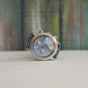 Pu&ograve; includere: Un orologio da polso cronografo argentato con quadrante blu e cinturino in denim blu.