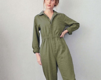 Puede incluir: Una mujer con un mono verde de trabajo con cierre de botones en la parte delantera y piernas remangadas. Lleva zapatillas blancas.