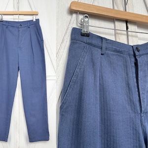 Könnte beinhalten: Eine blaue Jeanshose mit geradem Bein und Knopfleiste. Die Hose hat auf jeder Seite vorne eine Falte.