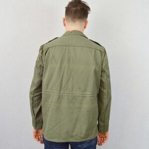 May include: A green utility jacket with a button-up front and a drawstring waist.