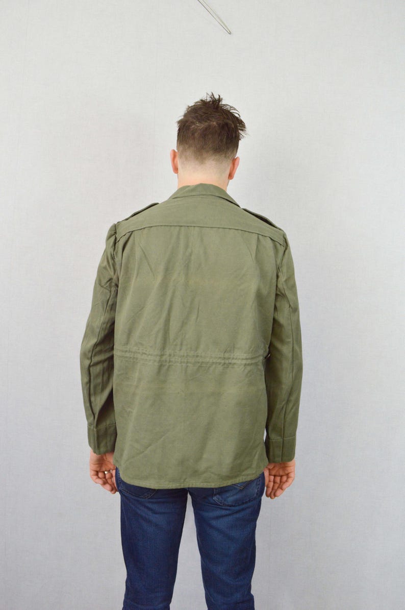 May include: A green utility jacket with a button-up front and a drawstring waist.