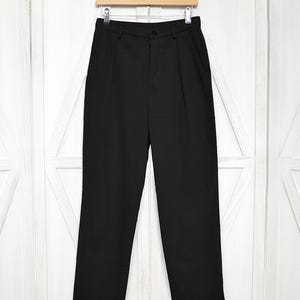 Könnte beinhalten: Schwarze, gefaltete Hose mit Knopfleiste und geradem Bein.