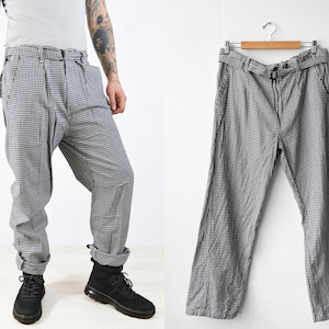 May include: Black and white checked trousers with a wide leg and a belt. The trousers are made of a lightweight fabric and have a relaxed fit.