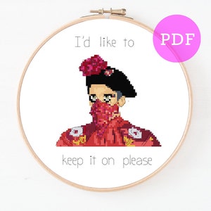 May include: Cross stitch pattern featuring a person wearing a red and white outfit with a red bandana and a flower on their head. The text "I'd like to keep it on please" is written below the person.