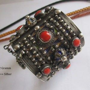 Könnte beinhalten: Ein silbernes Armband mit roten Korallen-Steinen und blauem und gelbem Emaille. Das Armband ist mit kleinen silbernen Perlen verziert und hat einen Verschluss. Das Armband wiegt 202 Gramm und ist aus 900+ Silber.