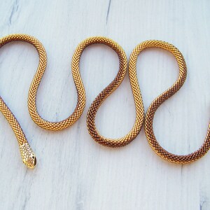 May include: A gold and brown beaded snake necklace with a gold snake head charm.