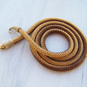 May include: A gold and brown beaded snake necklace with a snake head clasp.