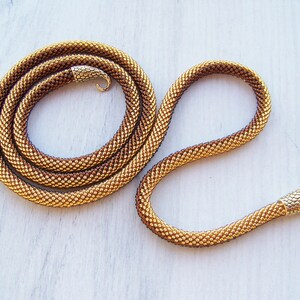 May include: A gold and brown beaded snake necklace with a gold snake head charm.