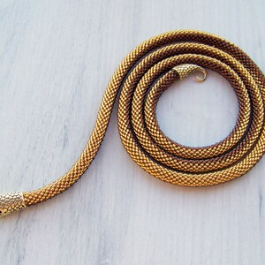 May include: A gold and brown beaded snake necklace with a gold snake head clasp.
