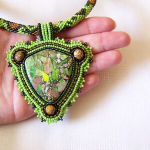 May include: A green and brown beaded necklace with a large green and brown stone pendant.