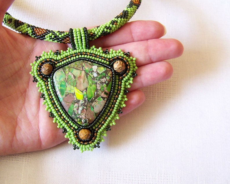 May include: A green and brown beaded necklace with a large green and brown stone pendant.