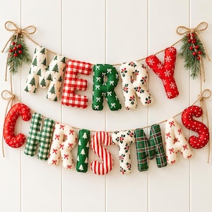 May include: A two-row fabric banner spelling MERRY CHRISTMAS with stuffed letters in various holiday patterns including red and white gingham, green plaid, pine trees, and holly. The letters are strung on twine with pine and berry accents.