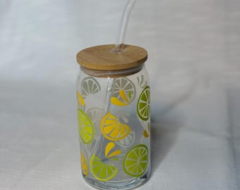 May include: A glass drinking bottle with a bamboo lid and a clear glass straw. The bottle has a lemon and lime design with yellow and green accents.