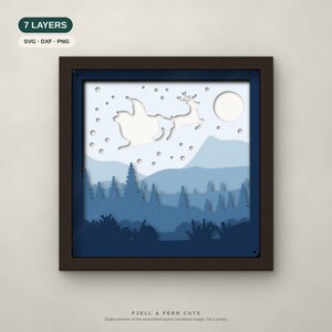 May include: A square framed 7-layer paper cut art piece featuring a silhouette of Santa in a sleigh with a reindeer flying over a snowy mountain landscape with pine trees and a full moon. The design includes text 7 LAYERS SVG DXF PNG.