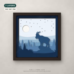 May include: A seven-layer paper cut art piece in a dark frame featuring a mountain goat standing on a rock in a forest landscape under a moon and starry sky. The design uses shades of blue and white. Text includes 7 LAYERS, SVG, DXF, PNG, and FJELL & FERN CUTS.
