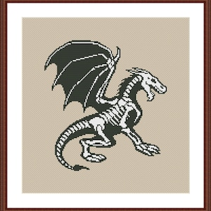 Pode incluir: Design de ponto cruz de um dragão esquelético em preto e branco. O dragão tem grandes asas e está em movimento sobre um fundo bege. A obra de arte é emoldurada em uma moldura de madeira marrom escuro.