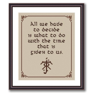 May include: A framed cross-stitch with a beige background and brown embroidery. The embroidery features the quote "All we have to decide is what to do with the time that is given to us." and a symbol.